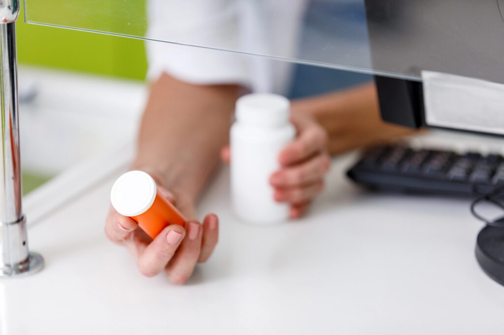 pharmacist holding medications covered by prescription cost savings programs